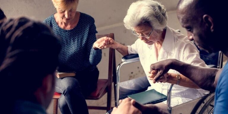 Elderly Group Holding Hands In Prayer Circle At Independent Living Facility