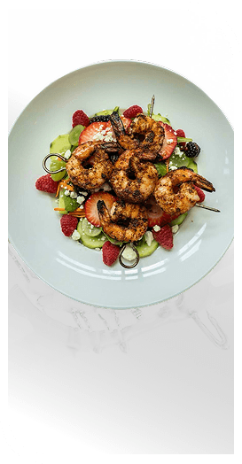 Grilled Shrimp Skewers Plated Over Fresh Berry Salad at an Independent Living Community
