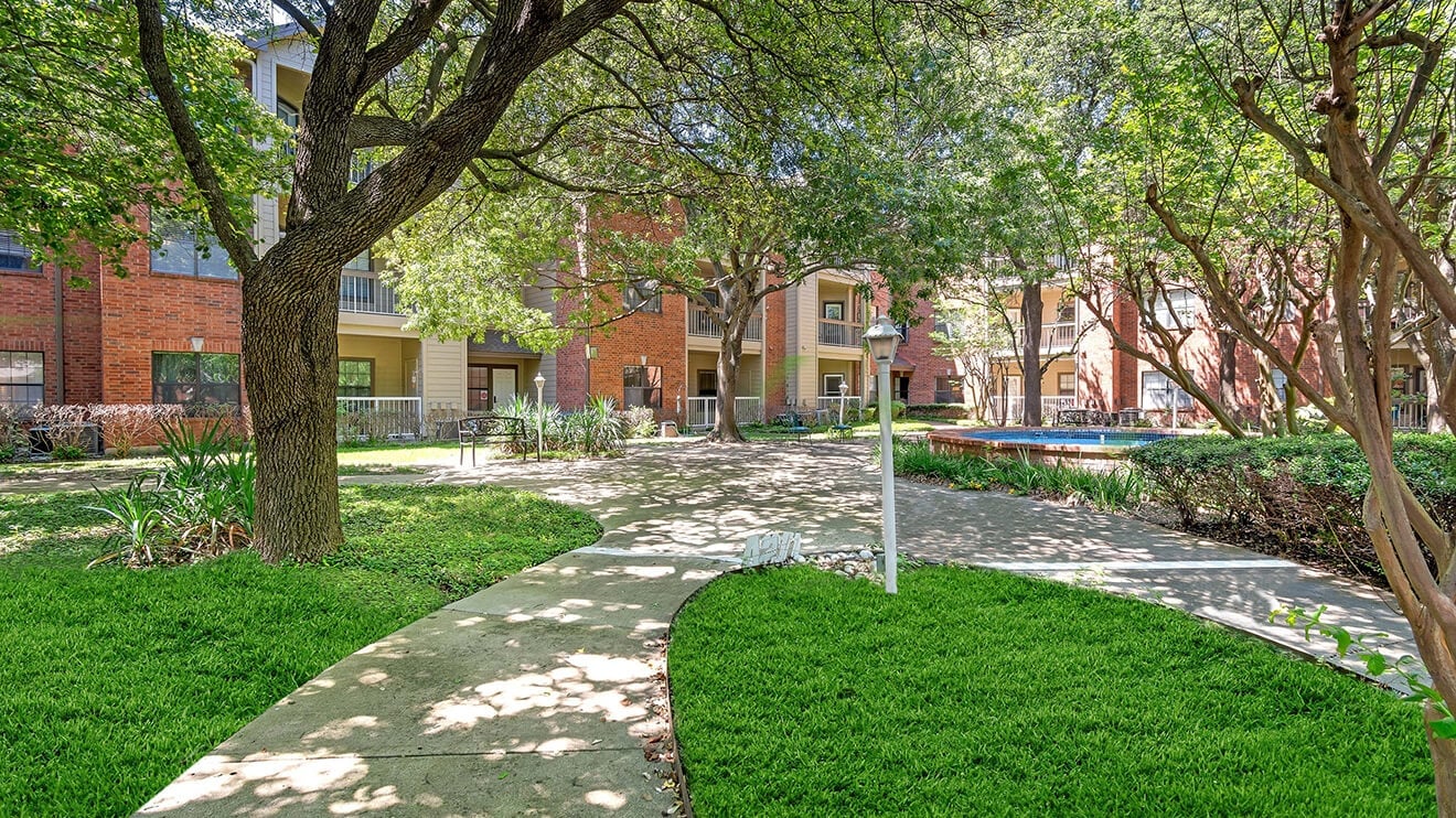 Shaded Courtyard Walkway with Lush Greenery and Trees at Our Independent Living Facility