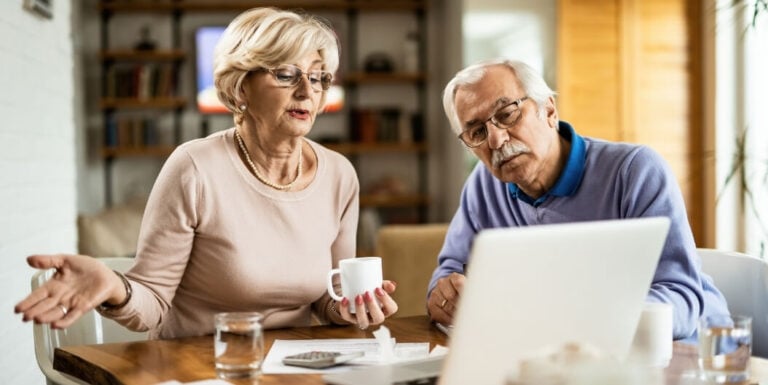 Elderly Couple Comparing Independent Living Facility Options on Laptop
